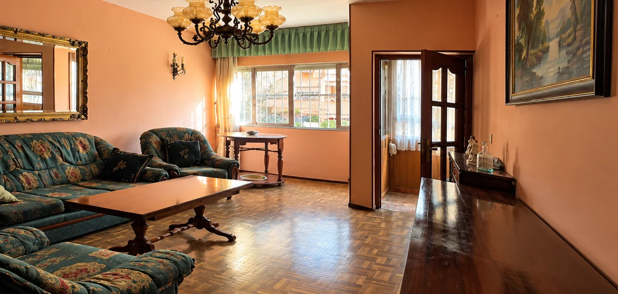 El mismo salón antes de la reforma: paredes color salmón, parqué de tablillas y carpintería de madera antigua